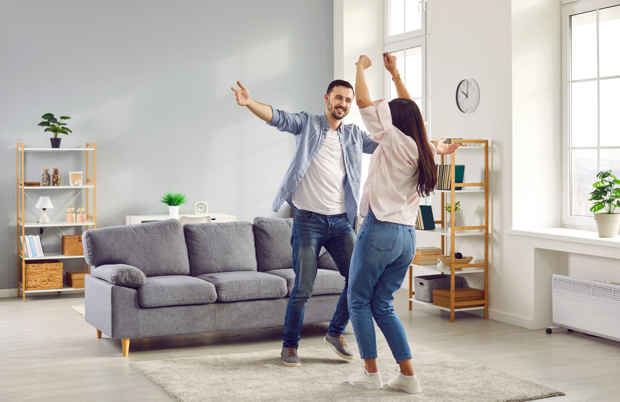 Happy family couple having fun together and dancing in the living room at home because they were able to pay off their mortgage early