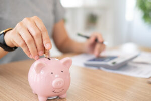 Savings,And,Finance,Concept.,Woman,Putting,Money,Coin,In,Piggy